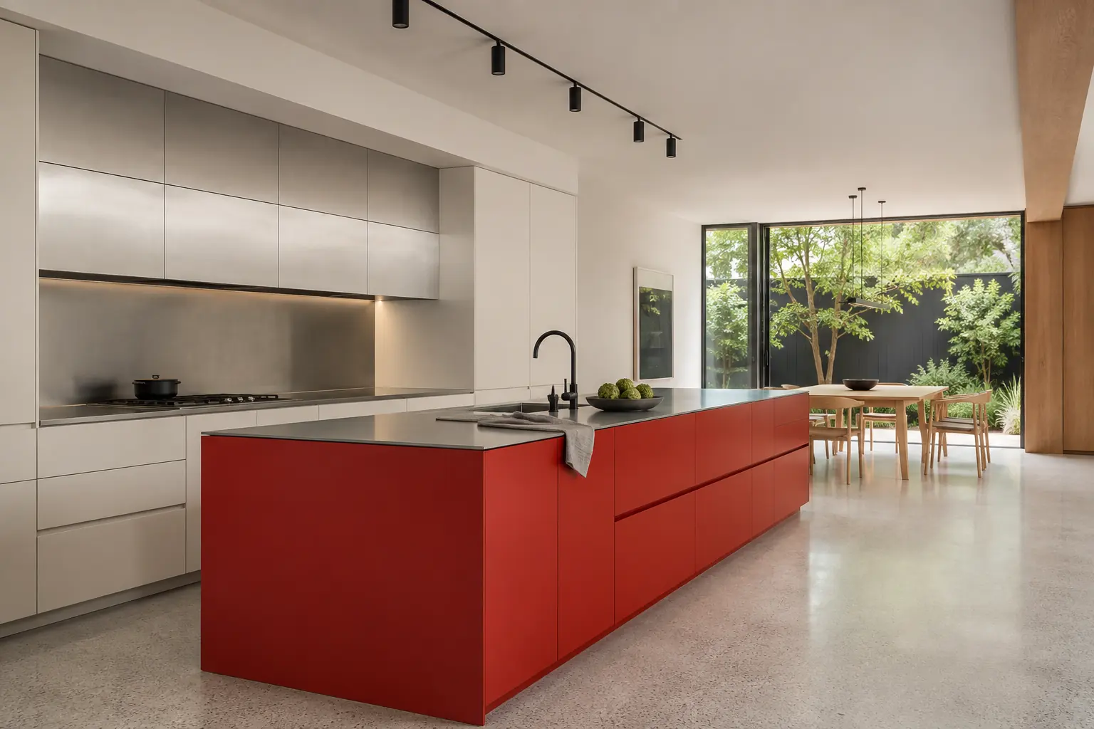Open fictional family kitchen with a signal-red island, pale ash dining table, and garden outlook